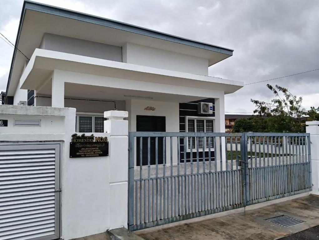 a white house with a gate and a fence at Seri Cempaka Homestay in Kluang