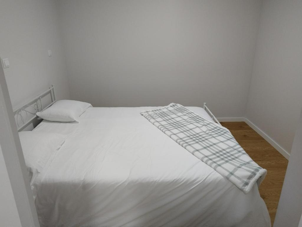 a bedroom with a white bed with a blanket on it at charnecas house in Gaula