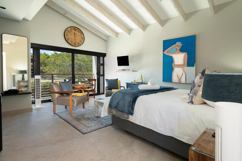 a bedroom with a bed and a clock on the wall at Topiary Lux Studio 16! in Herolds Bay