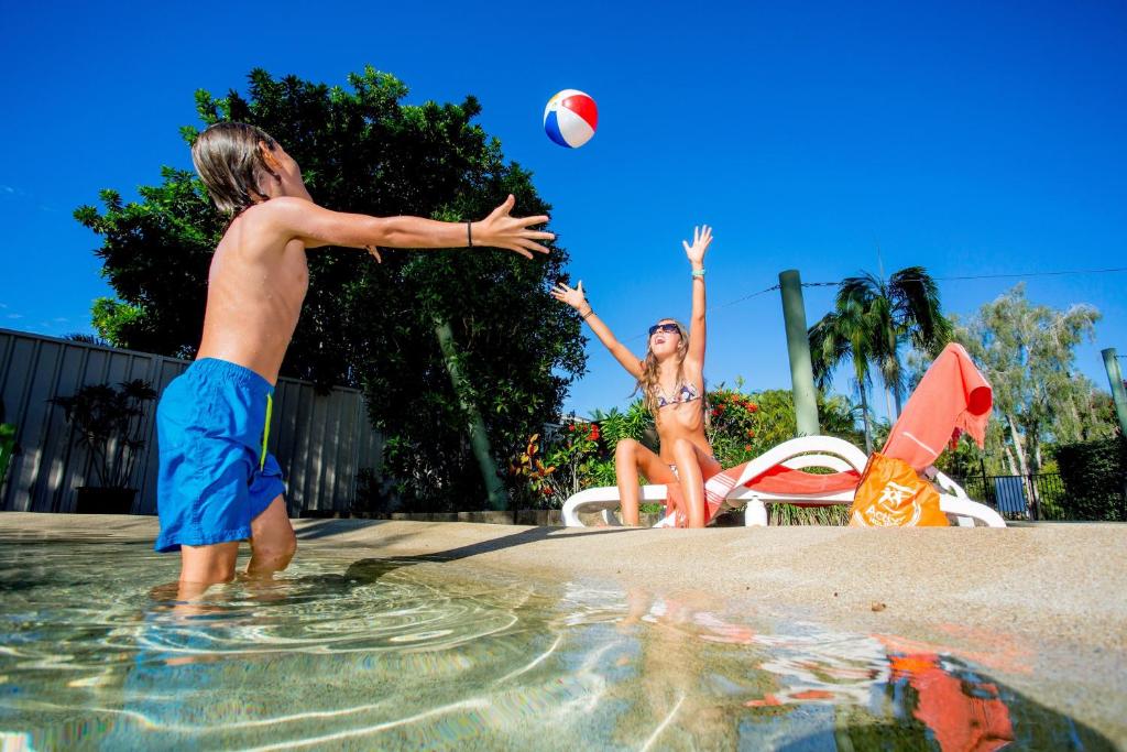 un hombre y una mujer jugando con una pelota de voleibol en una piscina en Ingenia Holidays Noosa, en Tewantin