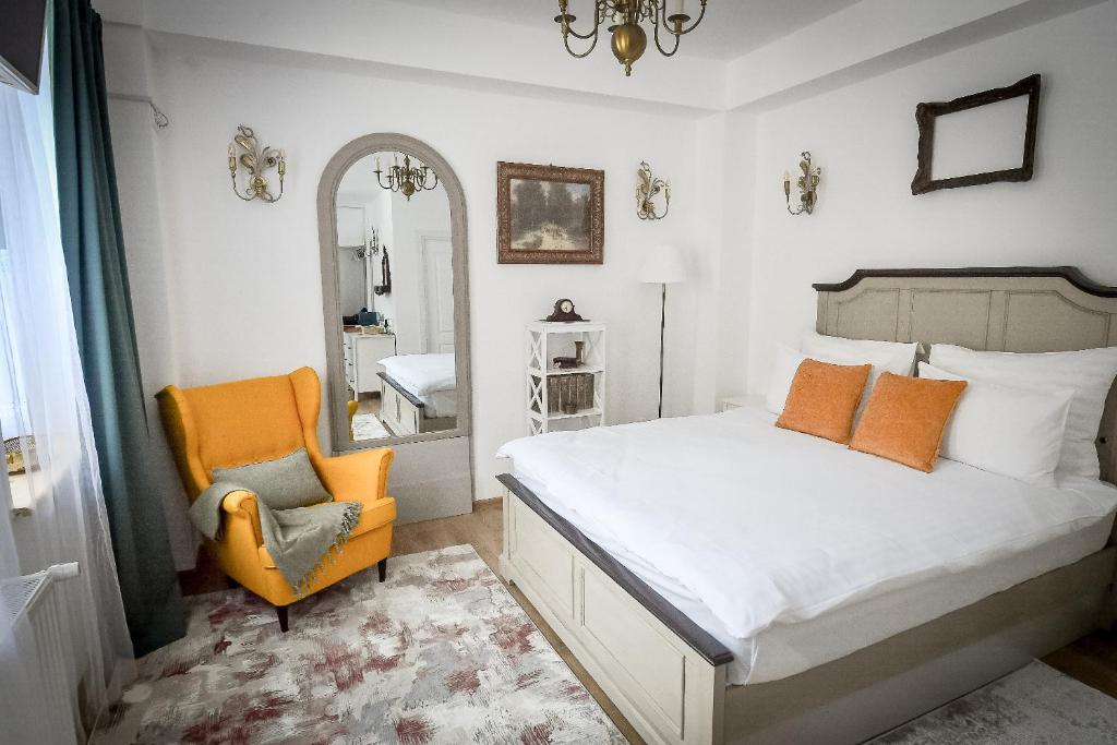 a bedroom with a bed and a chair and a mirror at Casa Baritiu Rooms in Braşov