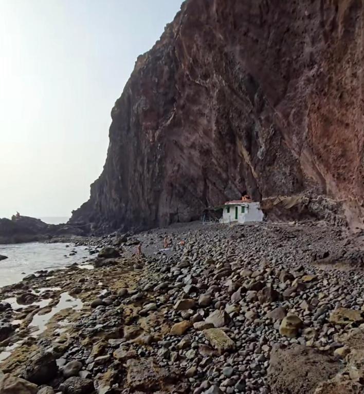 a house on a rocky beach next to a mountain at Casa Pavon in Montaña Alta