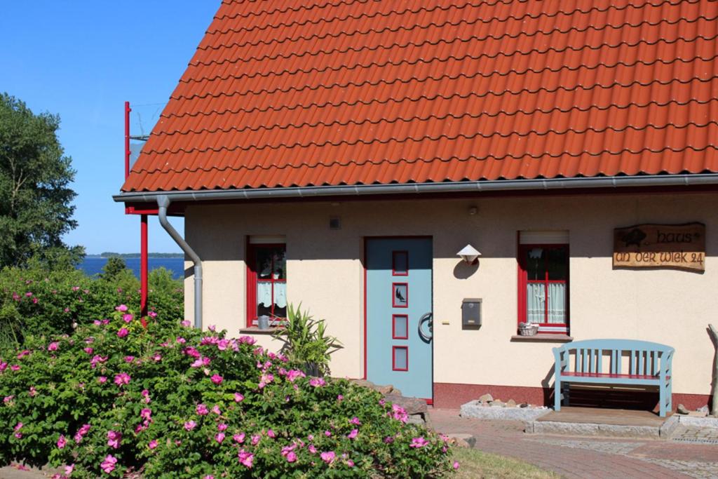 a house with a red roof with a bench in front at Haus an der Wiek in Wohlenberg