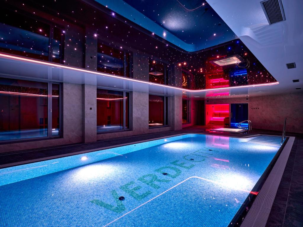 a swimming pool in a building with lights at Hotel Verde City in Koszalin