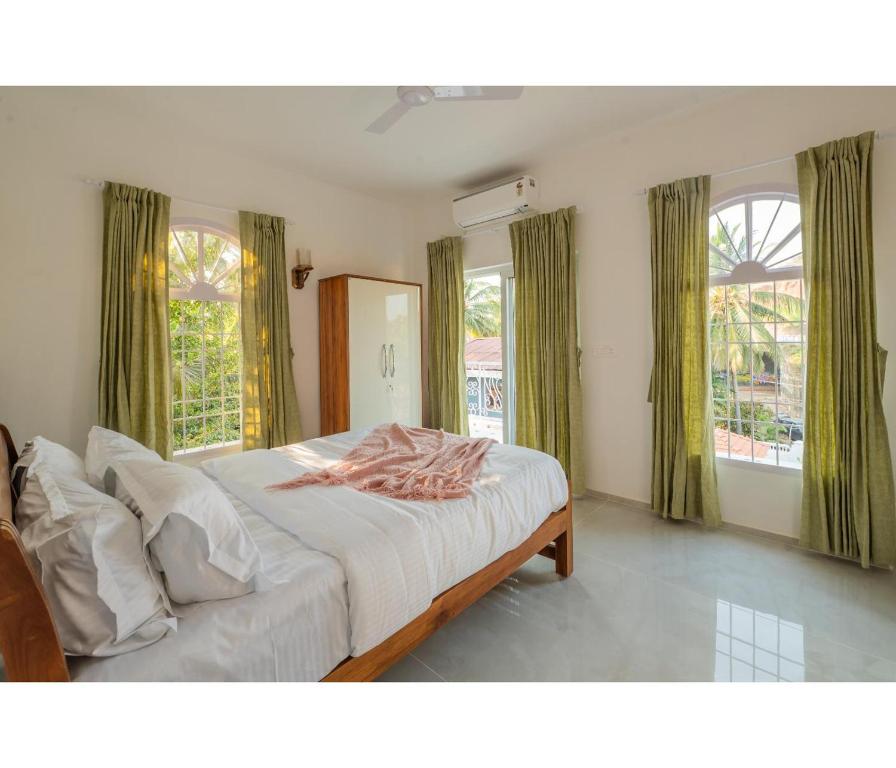 a bedroom with a large bed with green curtains at Casa De Alegria Goa in Canacona