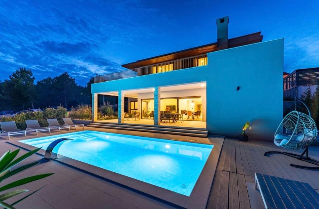 a villa with a swimming pool in front of a house at Villa Karpa in Pridraga
