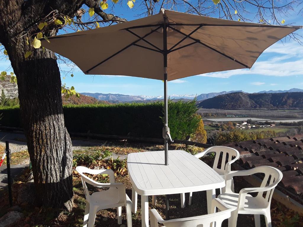 a white table and chairs with an umbrella at Maison au tilleul in Ribiers