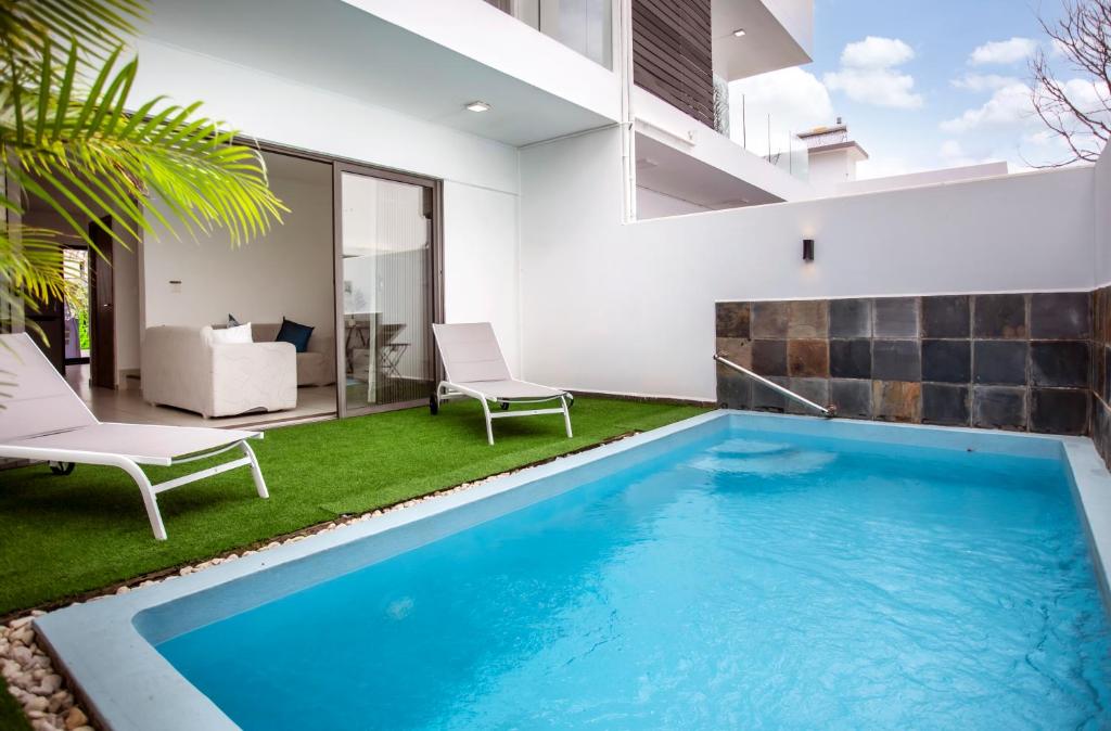 a swimming pool in a living room with a house at Stylish Central Three Bed Duplex with Private Pool in Flic-en-Flac
