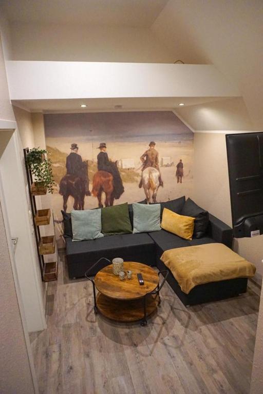 a living room with a couch and a painting on the wall at Wohnung Burghaus 5 OG in Krummhörn