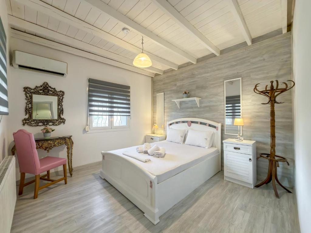 a bedroom with a white bed and a pink chair at Stone Haven & Garden near the Sea in Methoni
