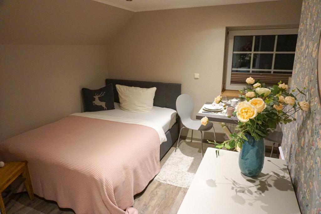 a bedroom with a bed and a table with a vase of flowers at Wohnung Burghaus 3 OG in Krummhörn