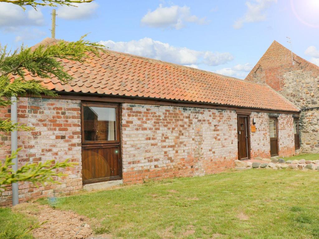a brick house with a wooden door and a yard at Meadow View in Hull
