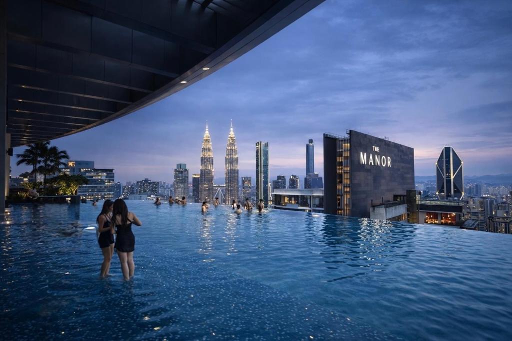 a group of people standing in a infinity pool on top of a city at IKON SUITE's E A T O N KLCC in Kuala Lumpur