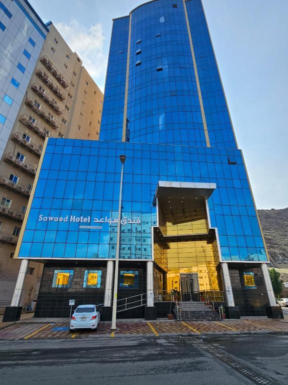 a blue building with a car parked in front of it at فندق سواعد العالمية مكة المكرمة الحرم - Sawaed International Hotel Makkah Al-Haram in Mecca