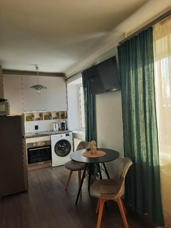 una cucina con tavolo e sedie e una cucina con fornelli di Studio Apartment 2 a Rēzekne
