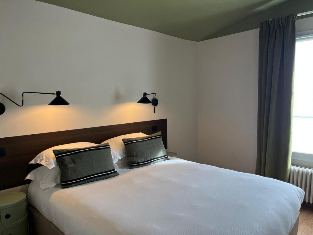 two laptops sitting on top of a white bed at Monsieur Jules Hôtel Clamart in Clamart