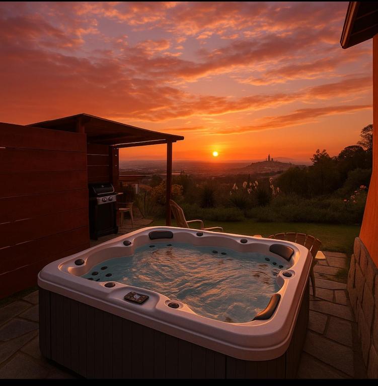 a hot tub with the sunset in the background at Panoramic View Village of Villa Luigina Cortona in Castiglion Fiorentino