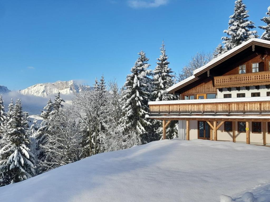 ein Haus auf einem schneebedeckten Hügel mit Bäumen in der Unterkunft Sonneckalm in Berchtesgaden in Berchtesgaden