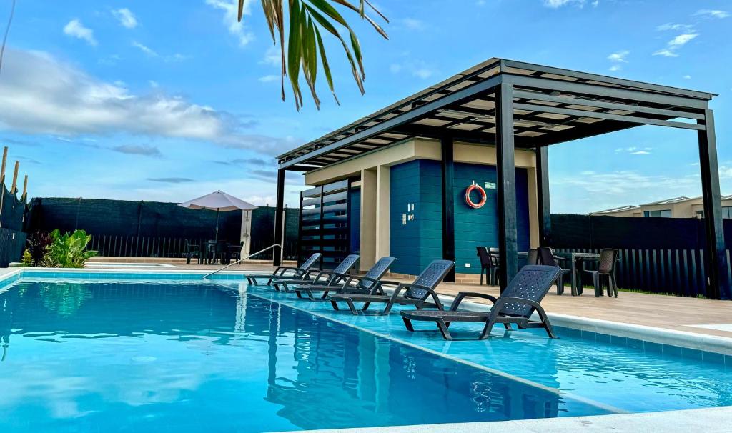 a swimming pool with chairs and a gazebo at Casa Turística en el Quindío in La Tebaida