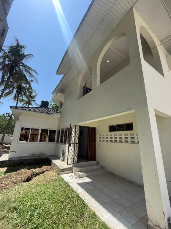 a white house with a palm tree in the background at Mtwapa- North Coast in Mtwapa