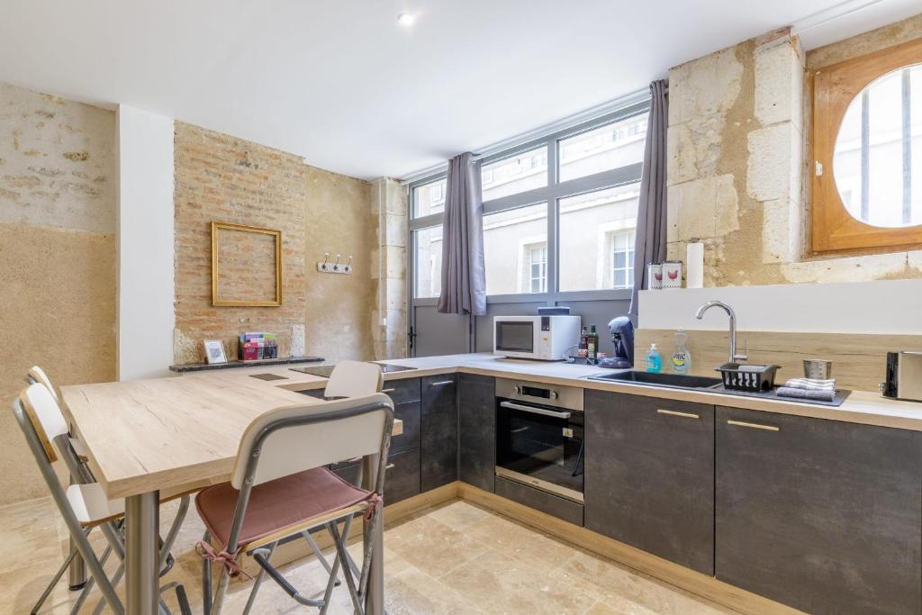a kitchen with a wooden table and a dining room at Cour des Moines - centre ville in Le Blanc