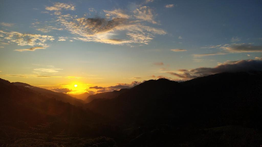 a sunset in the mountains with the sun in the sky at Vista cascada lodge in San Isidro de El General