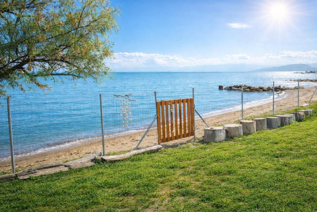 a gate on a beach near the water at Beachfront Bliss in Corfu - Vasiliki's Sea House in Lefkimmi