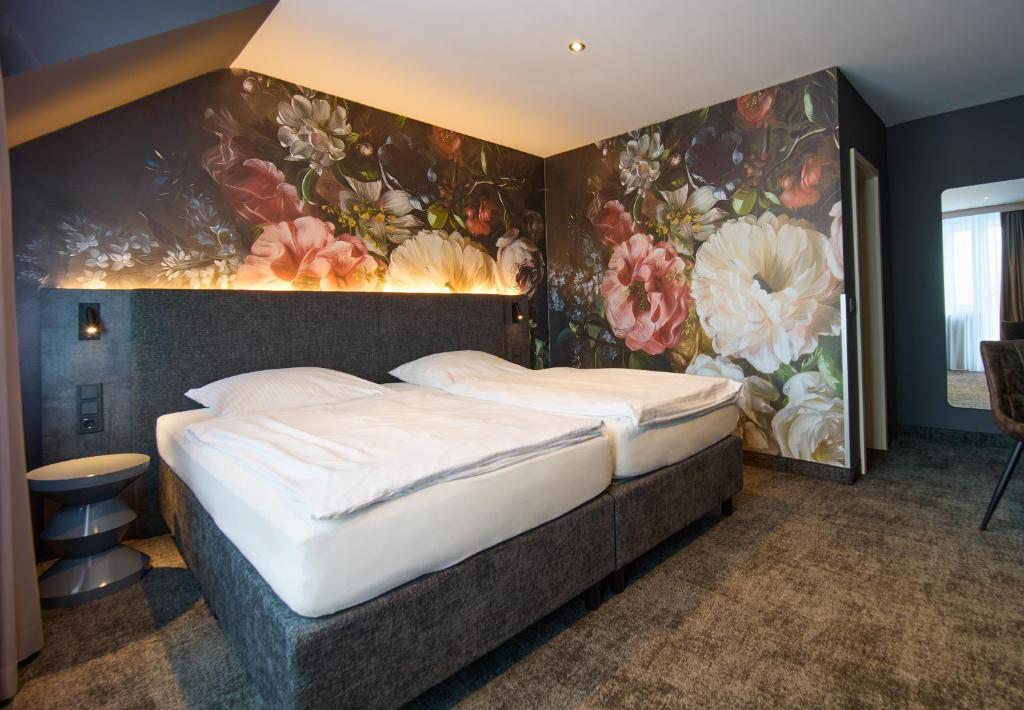 a bedroom with a large bed with flowers on the wall at Hotel Elsen in Grevenbroich