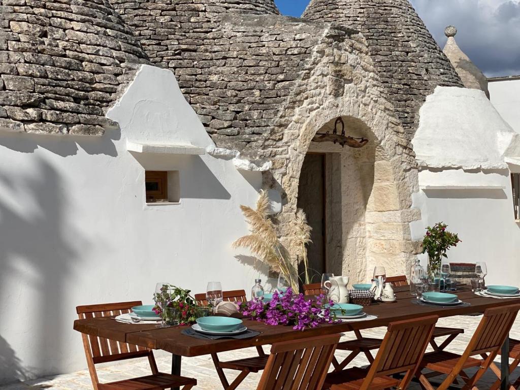 a wooden table in front of a stone building with a tableablish at Trullo al borgo in Cisternino