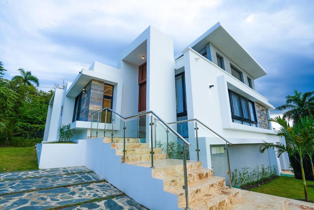 a white house with stairs in front of it at Modern Villa with a 15m Lap Pool, Cabarete in Cabarete