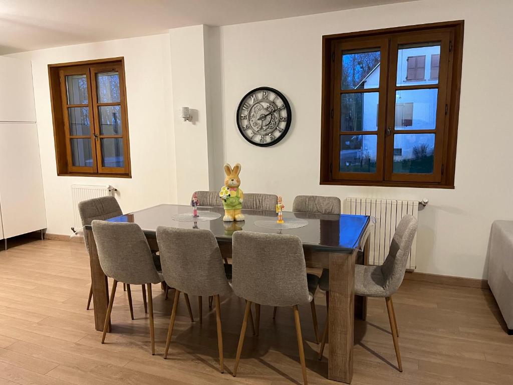 a dining room table with chairs and a clock on the wall at Escapade in Soulaines-Dhuys