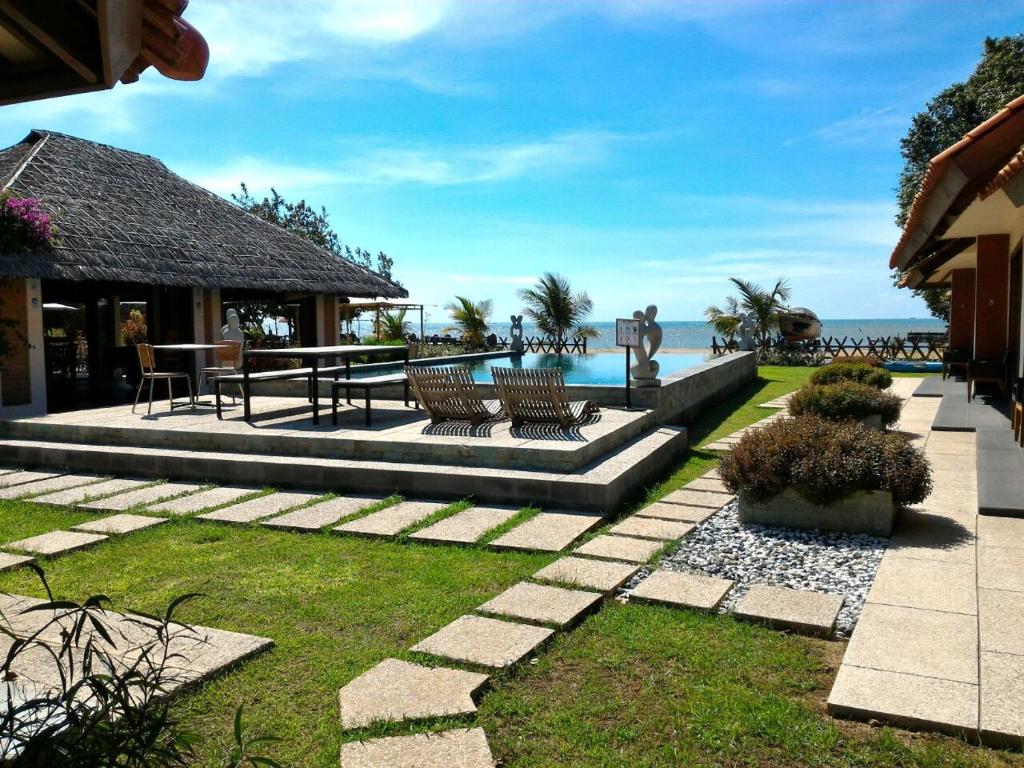 a patio with a table and chairs and the water at Jepara Marina Beach Bungalows in Jepara