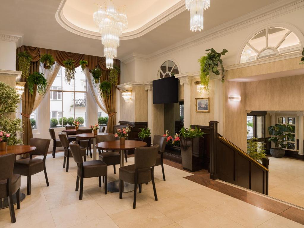 a restaurant with tables and chairs and a television at Royal Eagle Hotel in London
