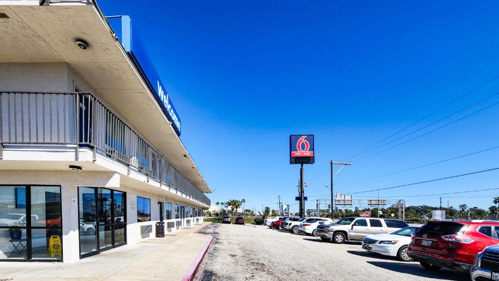 a parking lot with cars parked in front of a building at Studio 6 Galveston TX in Galveston