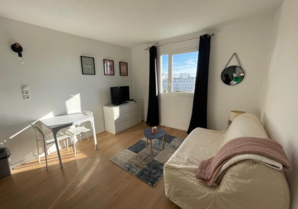 a living room with a white couch and a piano at Calais plage, superbe studio tout confort in Calais