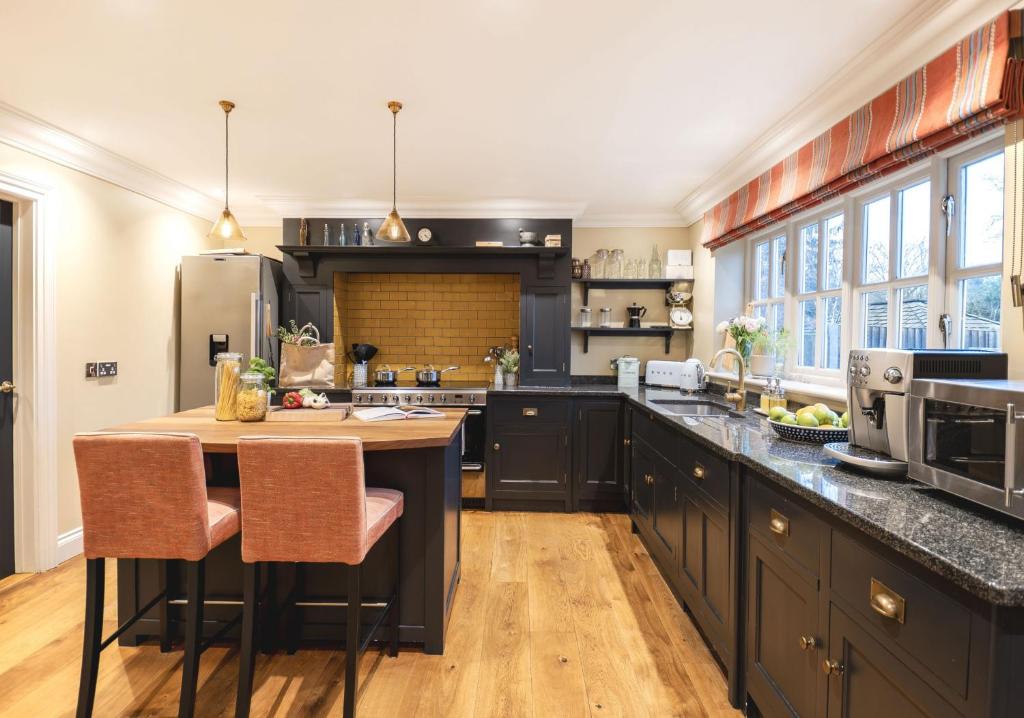 a kitchen with black cabinets and a island with bar stools at Kyuquot House in Woodbridge