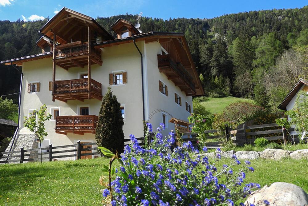 a building with balconies and flowers in a field at Hanslmoar Hof in Colli in Pusteria