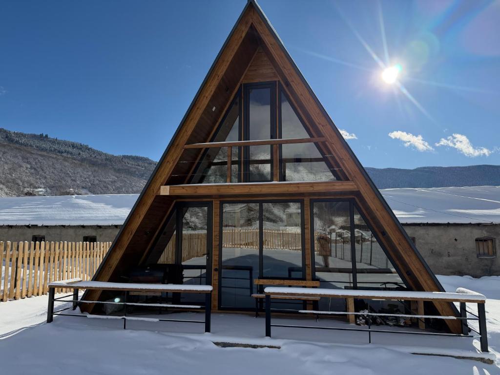 a triangular house with two benches in the snow at Mestia Inn Chalet in Mestia