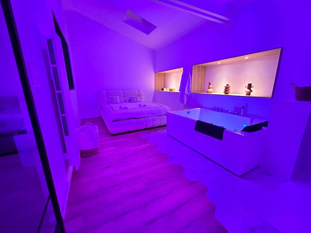 a purple room with a bed and a bath tub at Un toit pour 2 in Le May-sur-Èvre