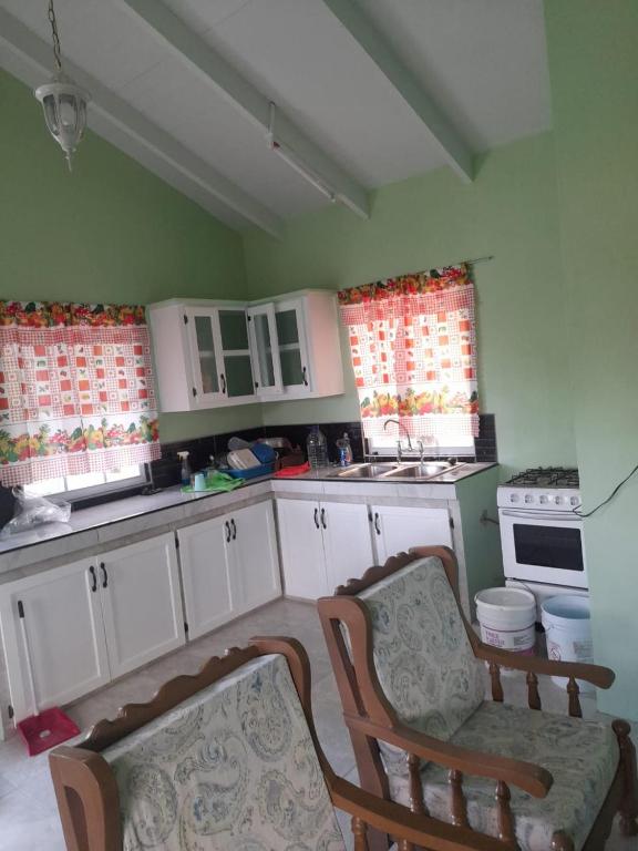 a kitchen with white cabinets and two chairs at Villa village 02 in Saint Lucia Island