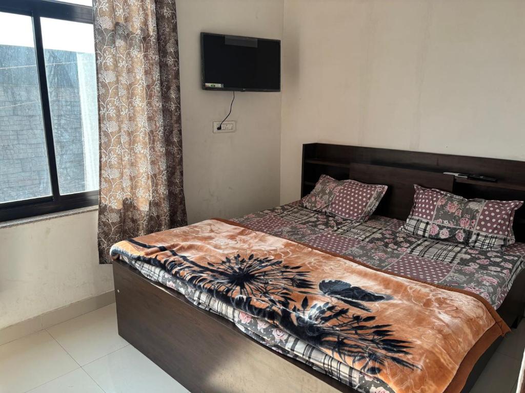 a bedroom with a bed and a television on the wall at Hotel Dausa Place in Dausa