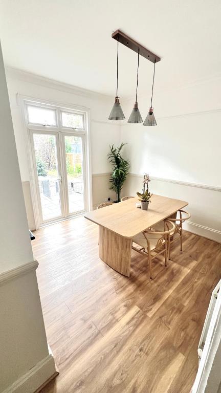 a dining room with a wooden table in a room at Modern Spacious 4 Bedroom Home in Greater LDN With Garden and Parking in Dartford
