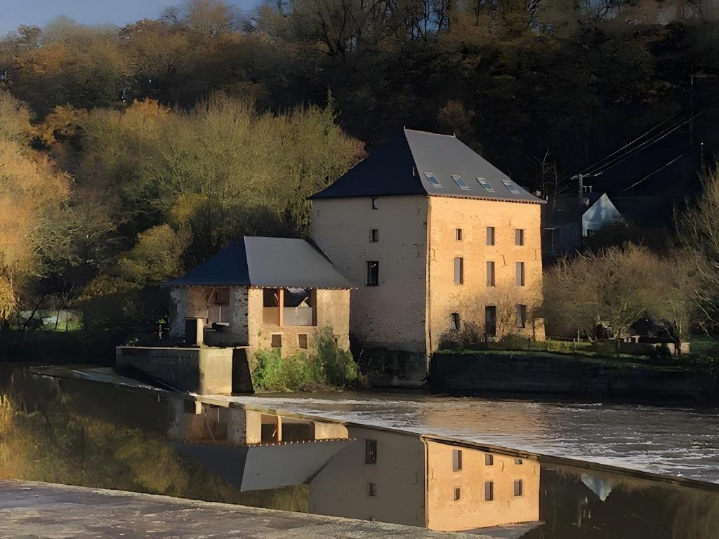 an old building next to a body of water at Moulin De La Benatre in Entrammes