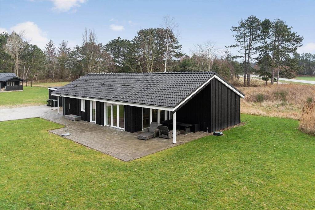 a black house with a patio in a field at 20514-Samso-Plantagevej-17 in Sælvig