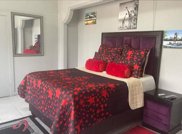 a bedroom with a red bed with red pillows at taoana guesthouse in Kroonstad