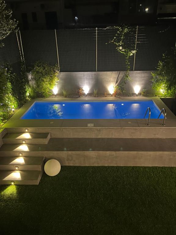 a swimming pool in a garden at night with lights at Trinity Gythion in Gythio