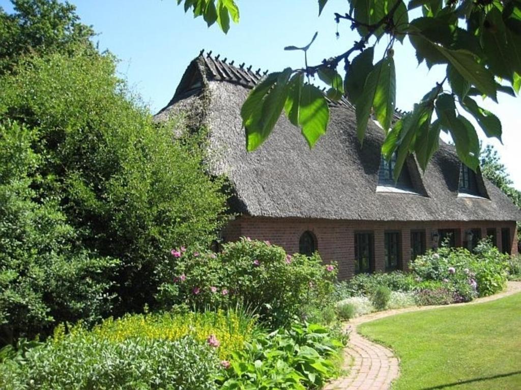 a brick house with a shingled roof and a garden at Ferienhaus von der Ahe in Mohrkirch