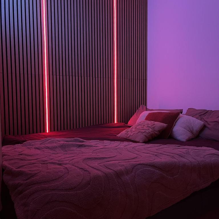 a bedroom with a bed with purple and pink lighting at Love room - Montélimar in Montélimar