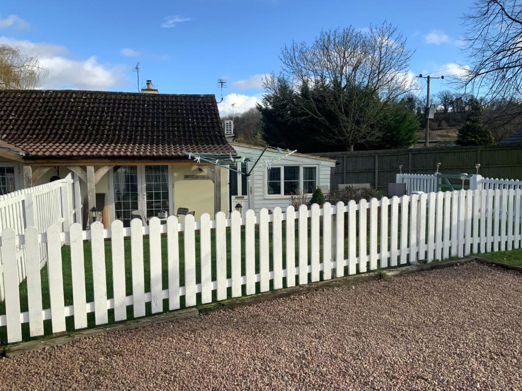 a white picket fence in front of a house at fairfeilds cottage Frog Trotters Bottom in Hartpury