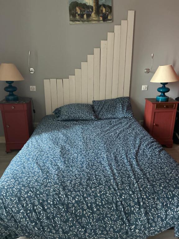 a bedroom with a bed with a blue comforter and two lamps at Chez Elie in Saintes